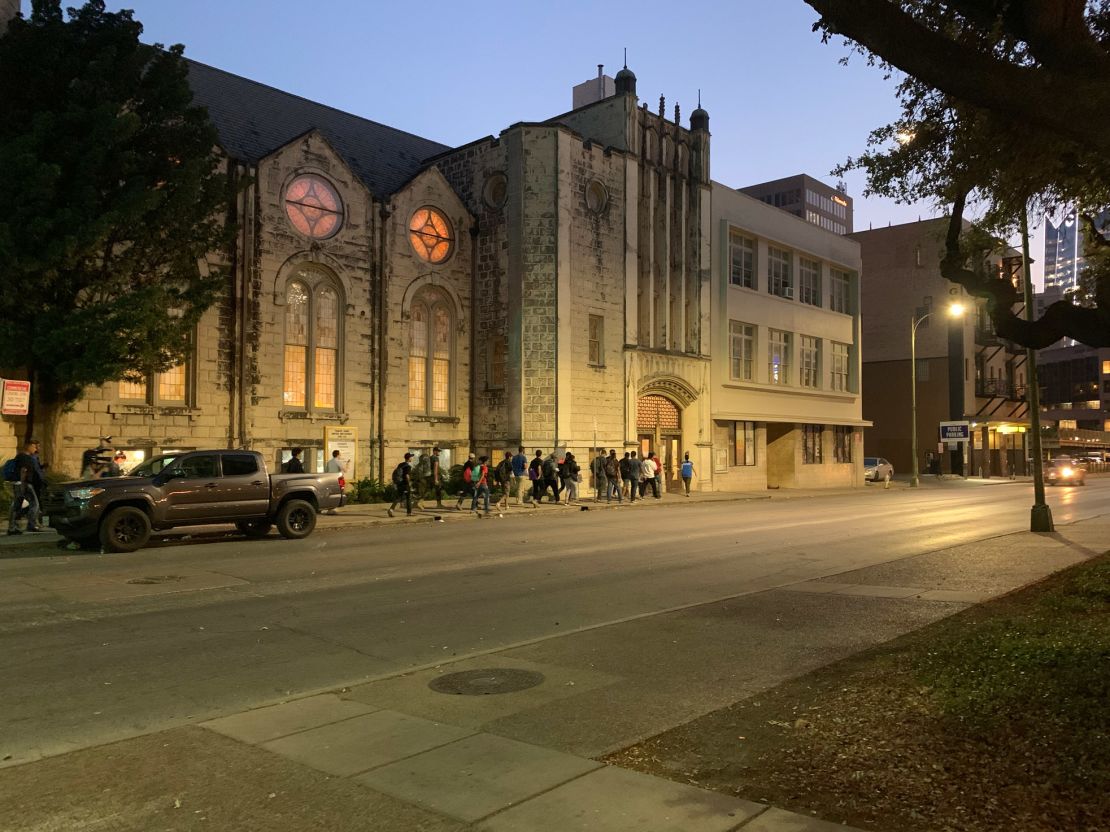 Every evening, migrants walk from Travis Park to Travis Park Church for overnight shelter. Pastor Gavin Rogers opened the shelter in the church's basement after migrants started sleeping outside in the park.