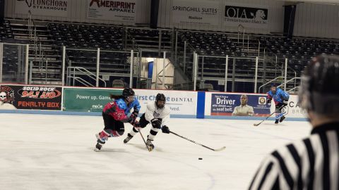 Danielle McLean, in pink and blue, battles another player for the puck at the Madison Gay Hockey Association game in November 2021.