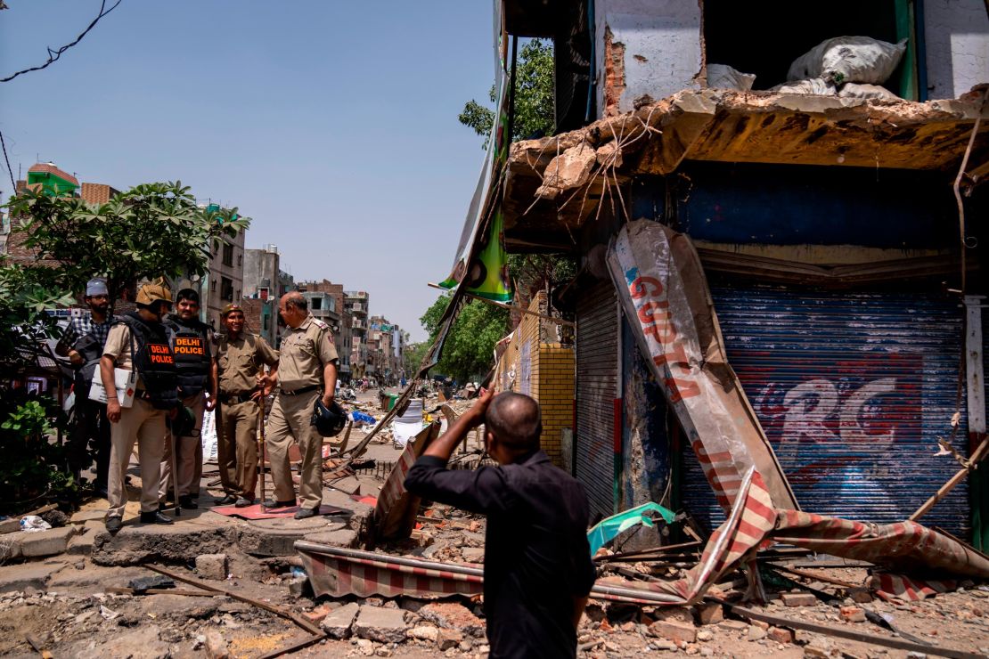 Policemen stand next to a partially demolished shop in the area that saw communal violence during a Hindu religious procession on Saturday, in New Delhi's northwest Jahangirpuri neighborhood, in New Delhi, India, Wednesday, April 20, 2022. 