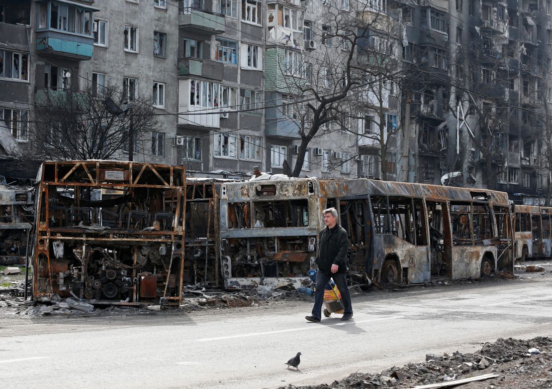 A local resident walks along a street past burnt out buses in Mariupol on April 19, 2022.