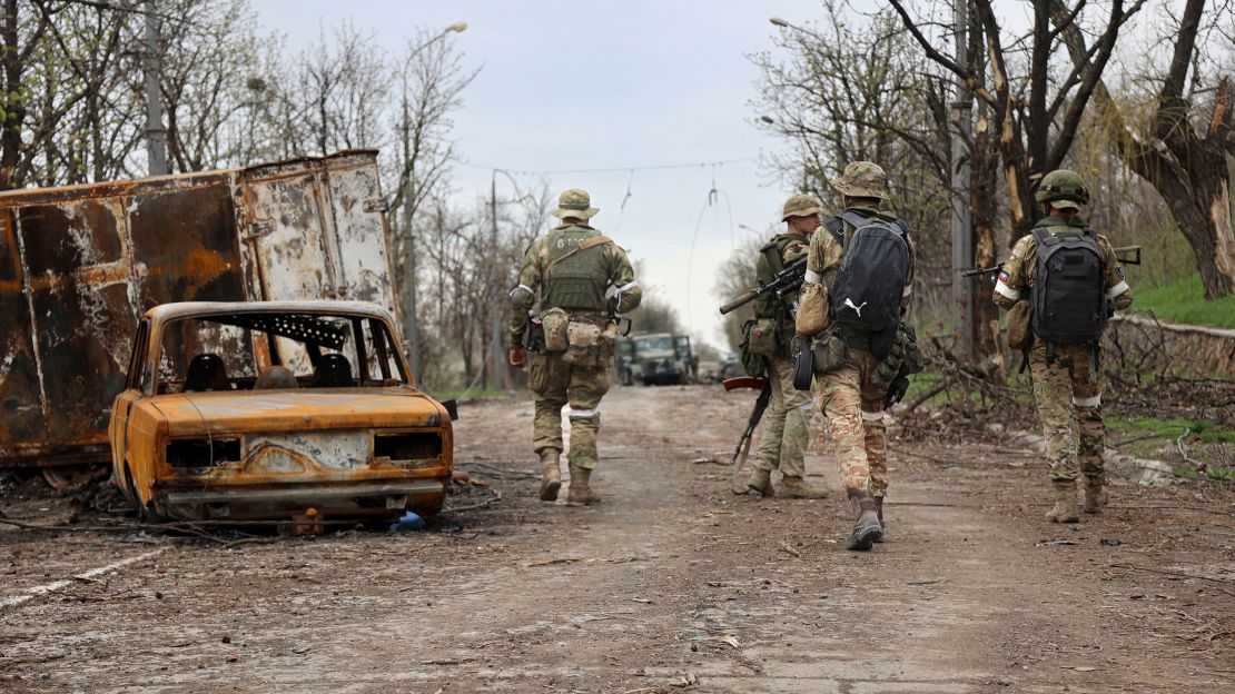 Servicemen of the pro-Russian Donetsk People's Republic militia walk past damaged vehicles during a heavy fighting in an area controlled by separatist forces in Mariupol.