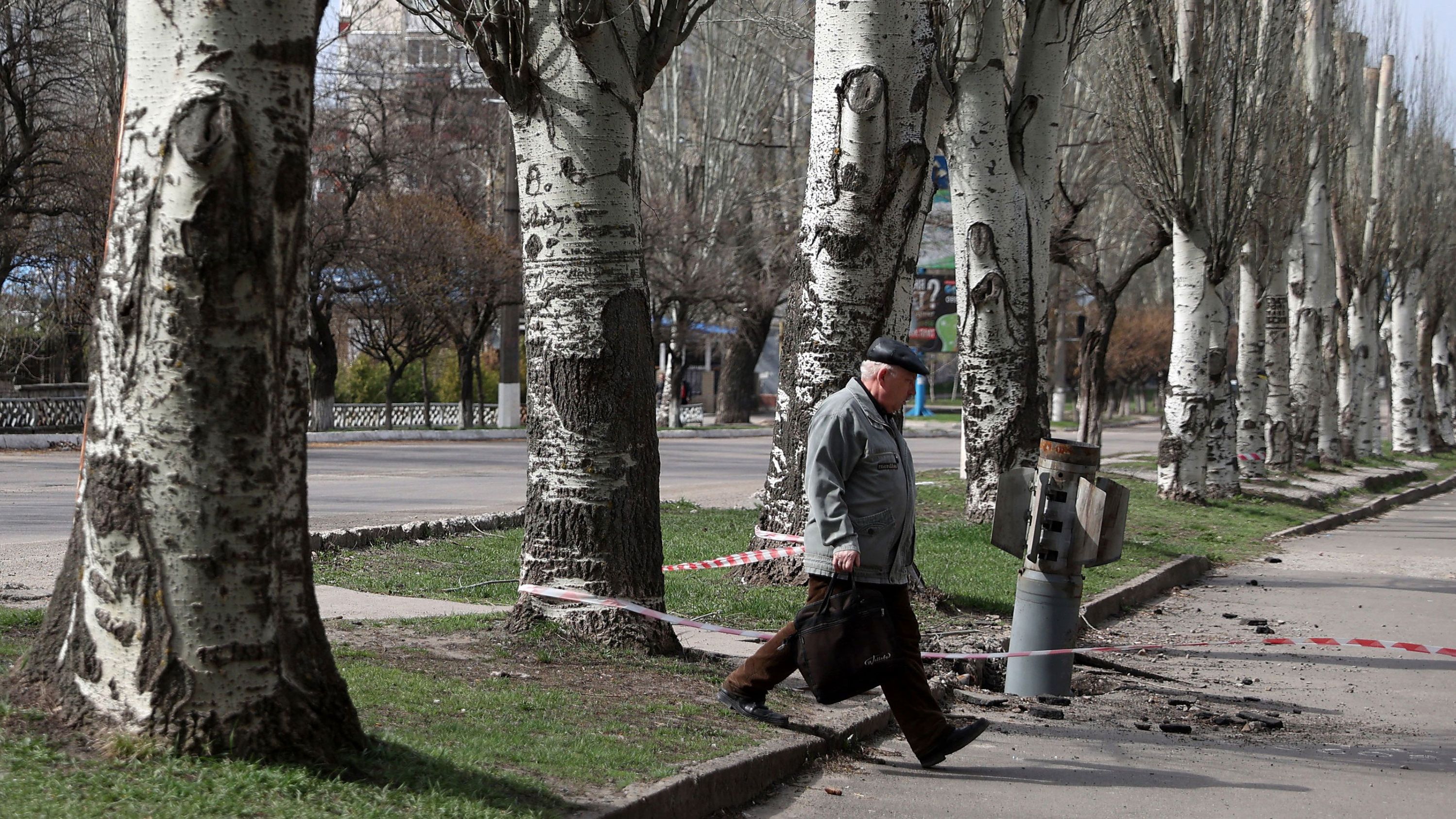 An elderly man walks past an unexploded tail section of a 300mm rocket embedded in the ground in Lysychansk, Luhansk region on April 11.