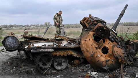 Ukrainian soldiers look at a destroyed Russian tank on a road in the village of Rosanio in the Kyiv region on April 16.
