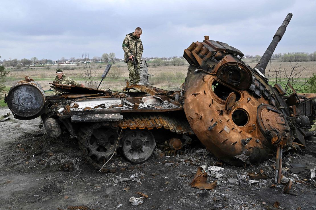 Ukrainian servicemen look at a destroyed Russian tank on a road in the village of Rusaniv, in the Kyiv region on April 16.