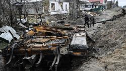 TOPSHOT - Local residents walk amid debris of a charred Russian tank next to destroyed houses in the village of Zalissya, northeast of Kyiv, on April 19, 2022, during the Russian invasion of Ukraine.