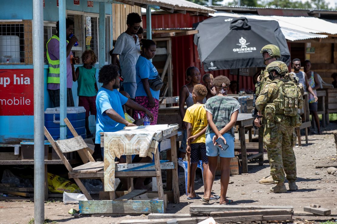 Australian Army soldiers talk with locals during a community engagement patrol through Honiara on November 27, 2021.