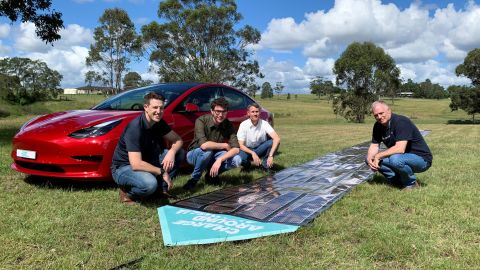 The team behind Charge Around Australia near a printed solar panel and Tesla car, in Gosforth, Australia on April 10.
