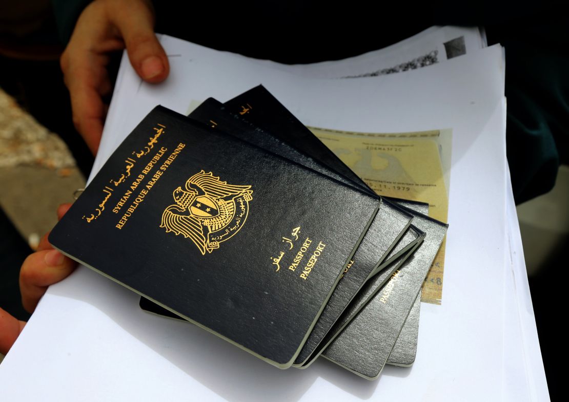 A refugee holds Syrian passports as she queues up to apply for immigration outside the German Embassy in Beirut in 2015. 