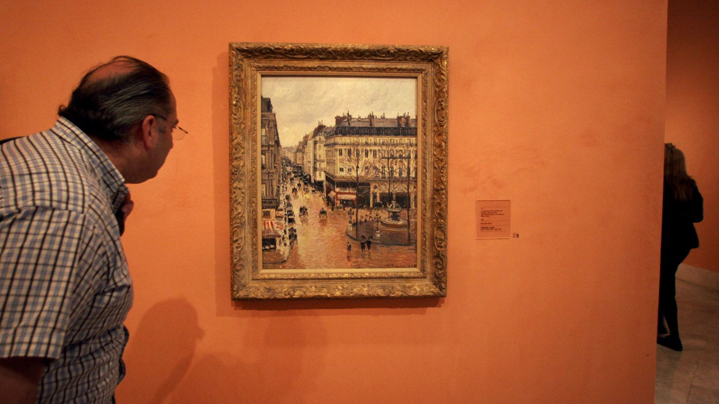 An unidentified visitor looks at the Impressionist painting by Camille Pissarro called the "Rue Saint Honoré, Afternoon, Rain Effect," in the Thyssen-Bornemisza Museum in Madrid, Thursday May 12, 2005. 
