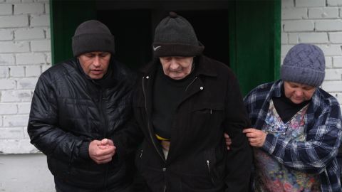 Vladimir helps lead his father Anatoly with the help of a neighbor. He buried his mother the day before.
