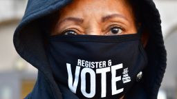 PHILADELPHIA, PA - OCTOBER 17:  Site manager Eileen Bowman wears a "REGISTER & VOTE" mask as long lines of voters wait to cast early voting ballots at Roxborough High School on October 17, 2020 in Philadelphia, Pennsylvania.  With the election only a little more than two weeks away, a new form of in-person early voting by using mail ballots, enables millions of voters have already cast their ballots.  President Donald Trump won the battleground state of Pennsylvania by only 44,000 votes in 2016, the first Republican to do so since President George Bush in 1988.  (Photo by Mark Makela/Getty Images)