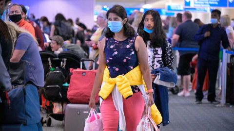 Some people continue to wear face masks this week such as these travelers at Orlando International Airport.