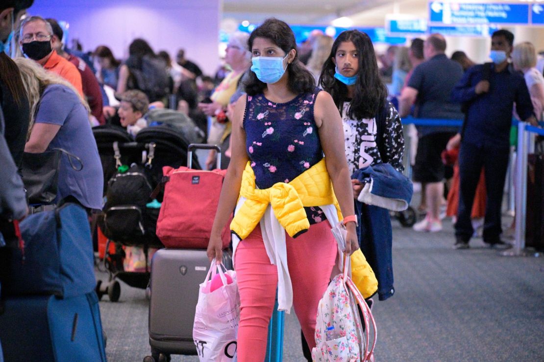 Some people continue to wear face masks this week such as these travelers at Orlando International Airport.