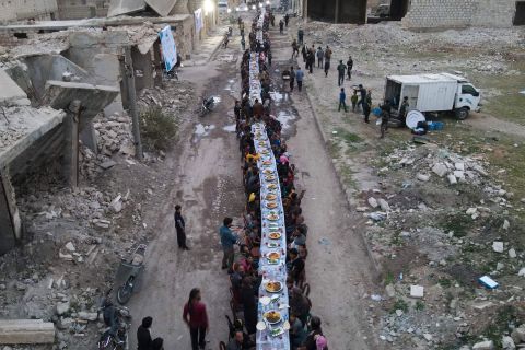People break fast together near damaged buildings in Tadef, Syria, on Monday, April 18. The Muslim holy month of Ramadan lasts until May 1.