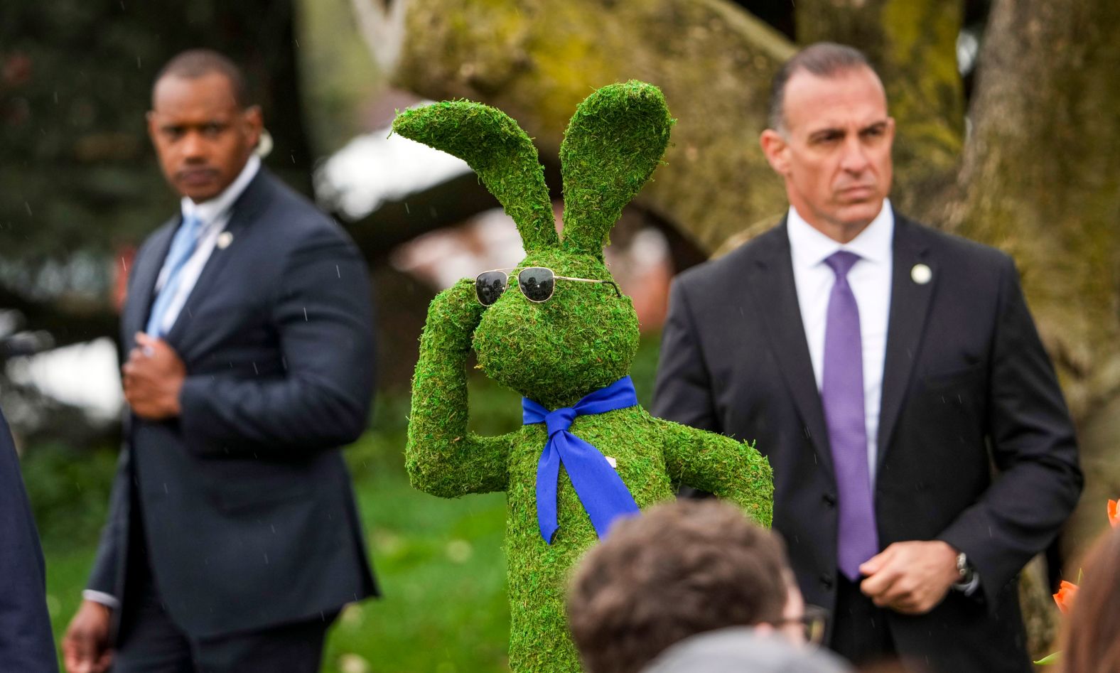 A shrub shaped like the Easter Bunny wears aviator sunglasses — a favorite of US President Joe Biden — near Secret Service agents who were attending the traditional <a href="index.php?page=&url=https%3A%2F%2Fwww.cnn.com%2F2022%2F04%2F18%2Fpolitics%2Fbidens-white-house-easter-egg-roll%2Findex.html" target="_blank">White House Easter Egg Roll</a> on Monday, April 18. It was the first Easter Egg Roll hosted by Biden since he took office.