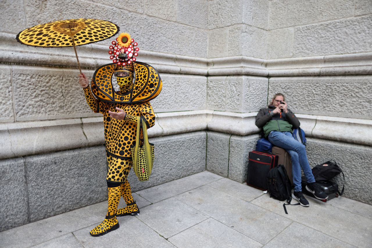 A costumed person stands next to a person waiting with bags during New York City's Easter Parade and Bonnet Festival on Sunday, April 17.