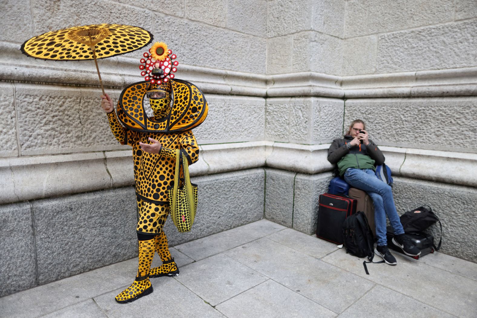 A costumed person stands next to a person waiting with bags during New York City's Easter Parade and Bonnet Festival on Sunday, April 17.