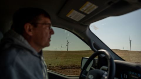 Wind turbines are seen in the distance from Scott Hampton's truck as he drives on a county road in Weatherford.