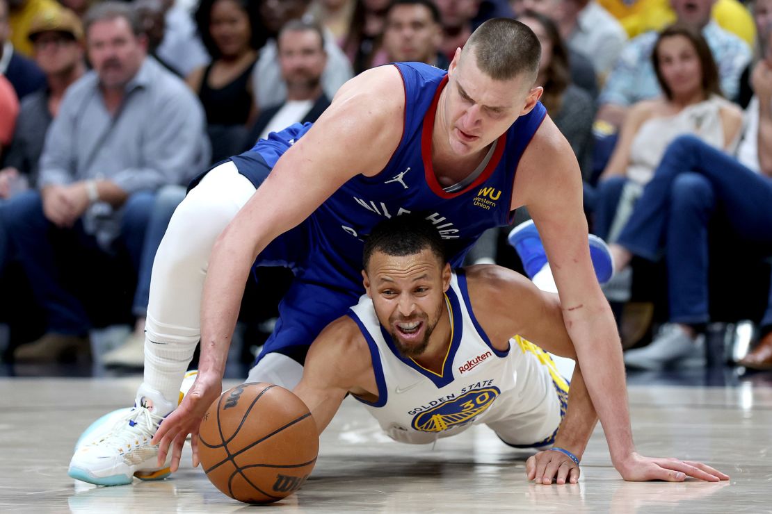 Nikola Jokic fights for a loose ball against Curry.