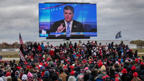 Supporters of President Donald Trump watch a video featuring Fox host Sean Hannity ahead of Trump's arrival to a campaign rally in Michigan on October 30, 2020.