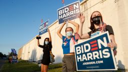 (L-R) Joud Elsherbiny, Jana E., and Heather McCluskie wave their Biden-Harris signs at the Town 'N Country Regional Public Library on November 3, 2020 in Tampa, Florida. After a record-breaking early voting turnout, Americans head to the polls on the last day to cast their vote for incumbent U.S. President Donald Trump or Democratic nominee Joe Biden in the 2020 presidential election.