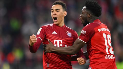 Jamal Musiala celebrates with teammate Alphonso Davies after scoring Bayern Munich's third goal.
