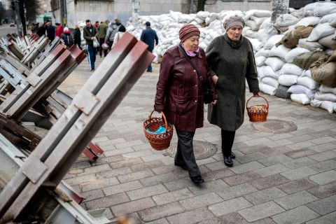 Women walk between sandbags and hedgehog anti-tank barricades to attend a blessing of traditional Easter food baskets on Holy Saturday in Zhytomyr, northwestern Ukraine on April 23.