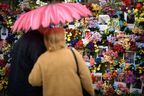 On April 24, a couple with a flower-design umbrella look at a floral memorial wall in Lviv, Ukraine for Ukrainian civilians killed during the Russian invasion.