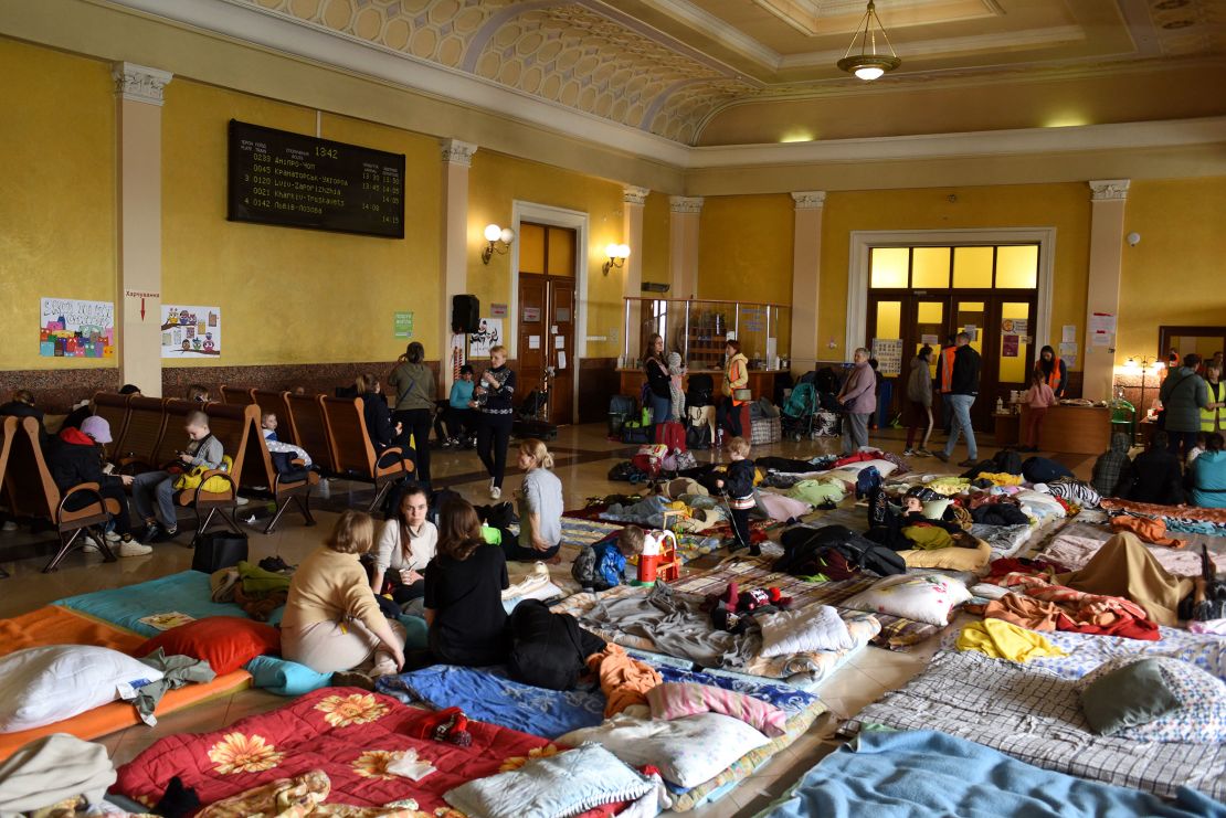 Women and children rest on wooden benches and mattresses in a room above Lviv train station. One corner has been converted into a children's play area, with toys, books and games.