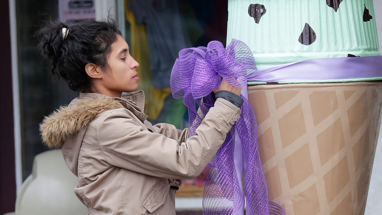 Ingrid Sievers ties a ribbon in front of an ice cream shop on April 26 as officials investigate the homicide.