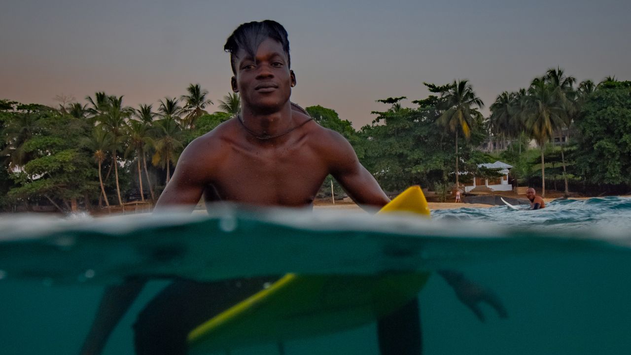 Oscar Comney, Massalley's older brother and former national surf champion, poses at dusk. Despite shared boards and sometimes broken equipment, the local scene continues to grow, with an annual surf competition having taken place in Robertsport for the past eight years.