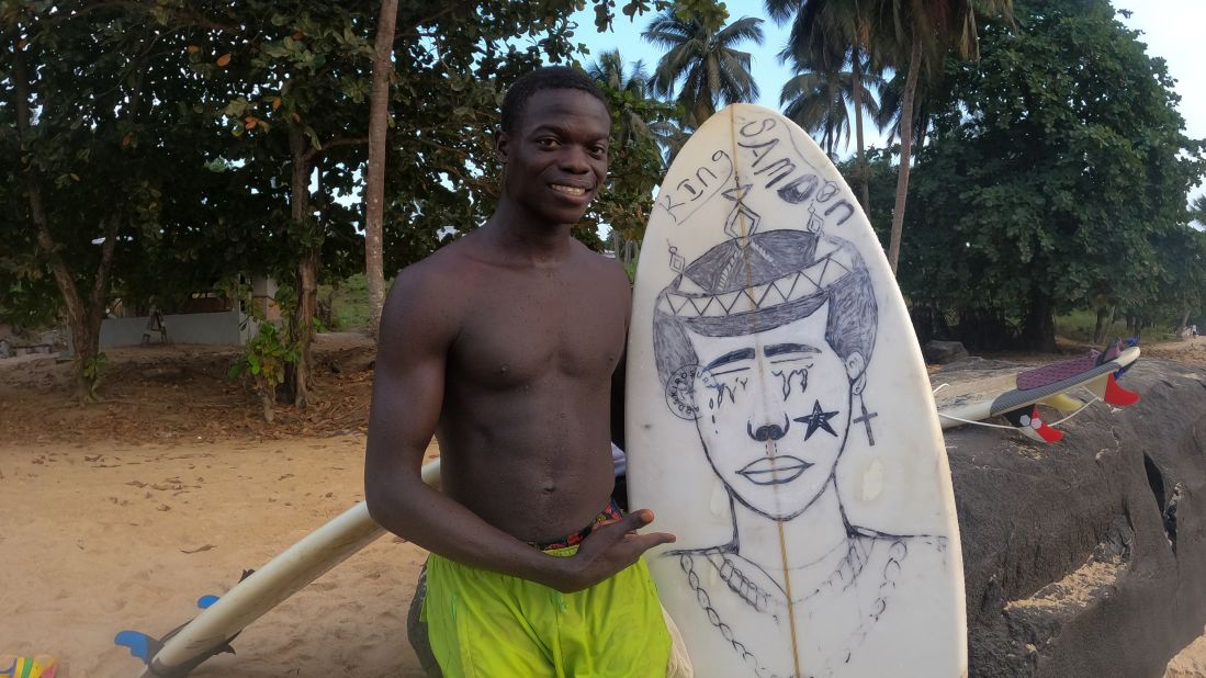 Comney, 17, shows off a surfboard. Equipment including boards and wax is donated, either by departing tourists or by Swiss NGO Provide the Slide, and shared between local surfers.