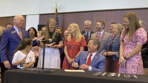 Georgia Gov. Brian Kemp laughs with state Senate President Pro Tem Butch Miller and others as he signs education bills into law on Thursday, April 28, 2022 in Cumming, Georgia. 