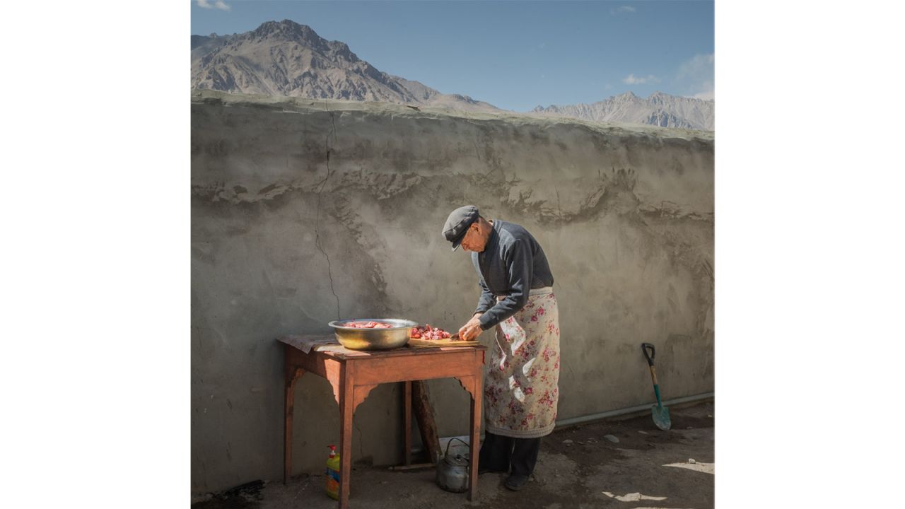 <strong>The Philip Harben Award for Food in Action winner | Weining Lin of China | "Cook":</strong> An elderly man is preparing food in a courtyard bathed in sun. He finely cuts meat and puts it in a basin. This is a common scene in a farm yard.