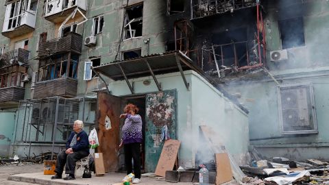 Local residents are seen outside an apartment building damaged in Mariupol on April 28, 2022. 