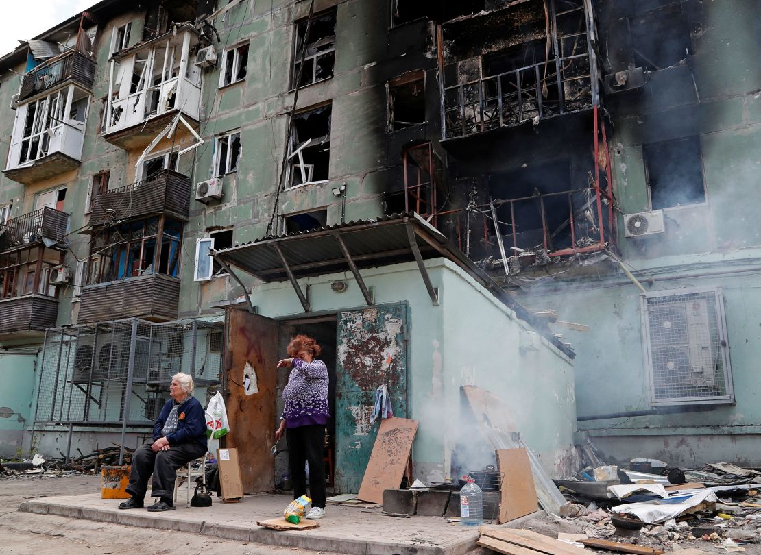 Local residents are seen outside an apartment building damaged in Mariupol on April 28, 2022. 