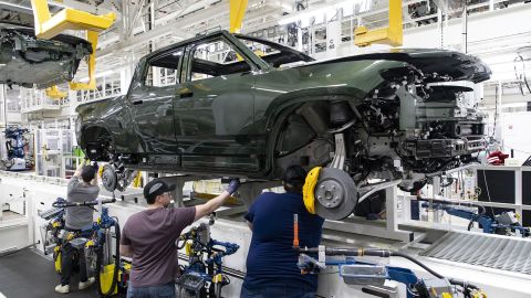 Workers lower an R1T truck body onto a chassis in the assembly line, April 11, 2022, at the Rivian electric vehicle plant in Normal, Illinois.