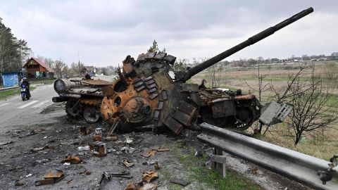 A man rides a motorbike past a destroyed Russian tank on a road in the Kyiv region on April 16.