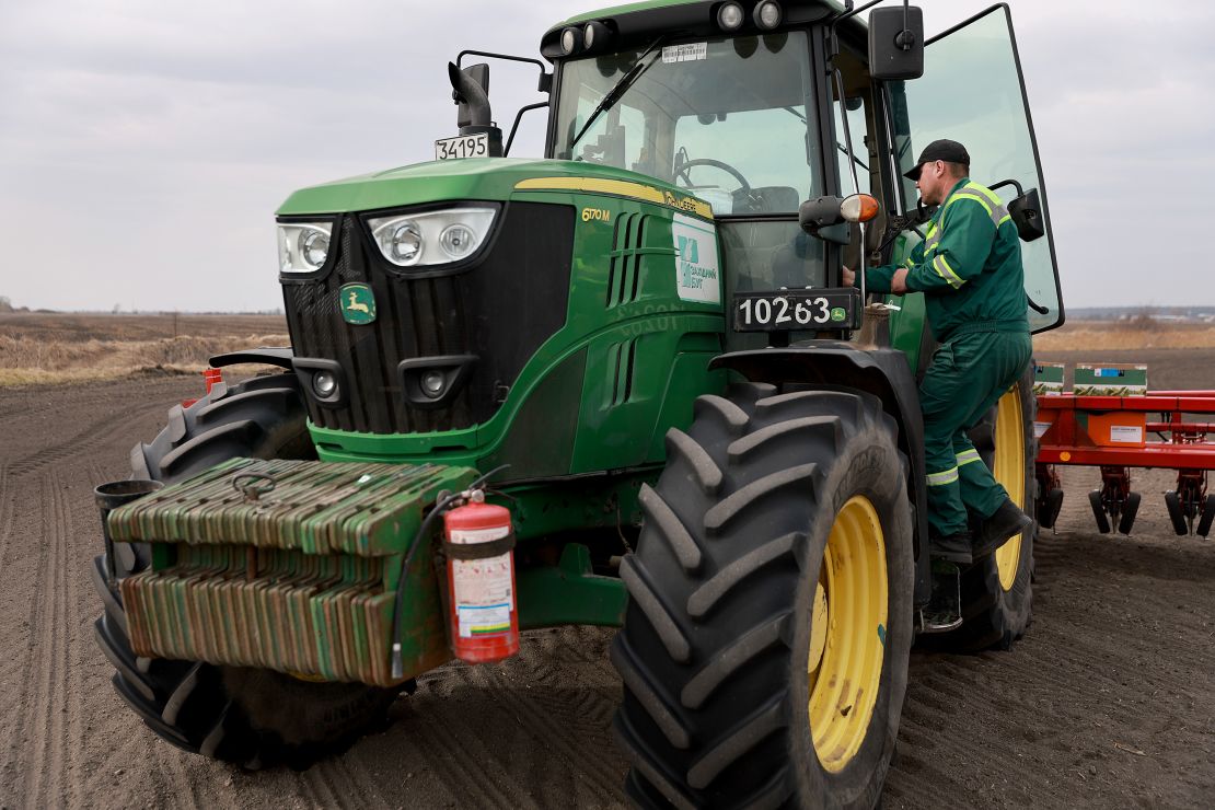 Ukrainian farmer Morda Vasyl steps into the cab of a John Deere tractor.