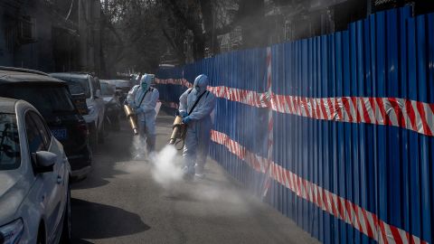 Workers in protective suits disinfect an area outside a barricaded community that was locked down for health monitoring after recent cases of Covid-19 were found in the area on March 28, in Beijing, China. 