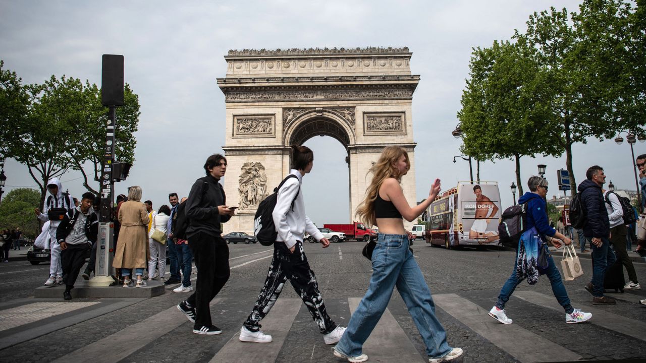 Pedestrians cross the Champs-Élysées in front of the Arc de Triomphe monument in Paris on April 29, 2022. France is at Level 3, or "high" risk for Covid-19.