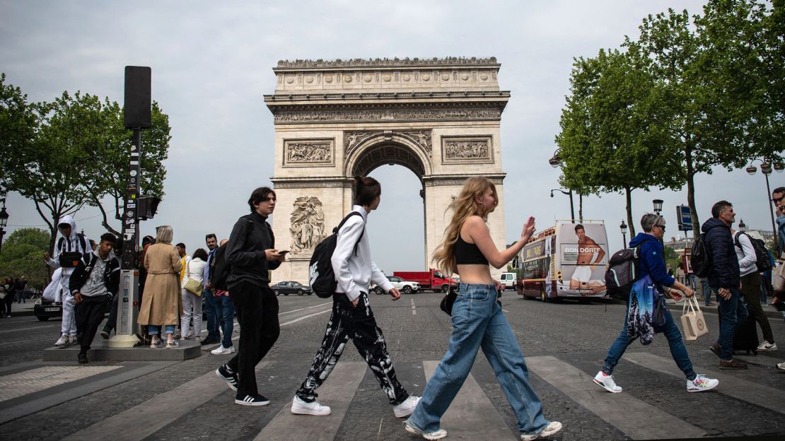 Pedestrians cross the Champs-Élysées in front of the Arc de Triomphe monument in Paris on April 29, 2022. France is at Level 3, or "high" risk for Covid-19.