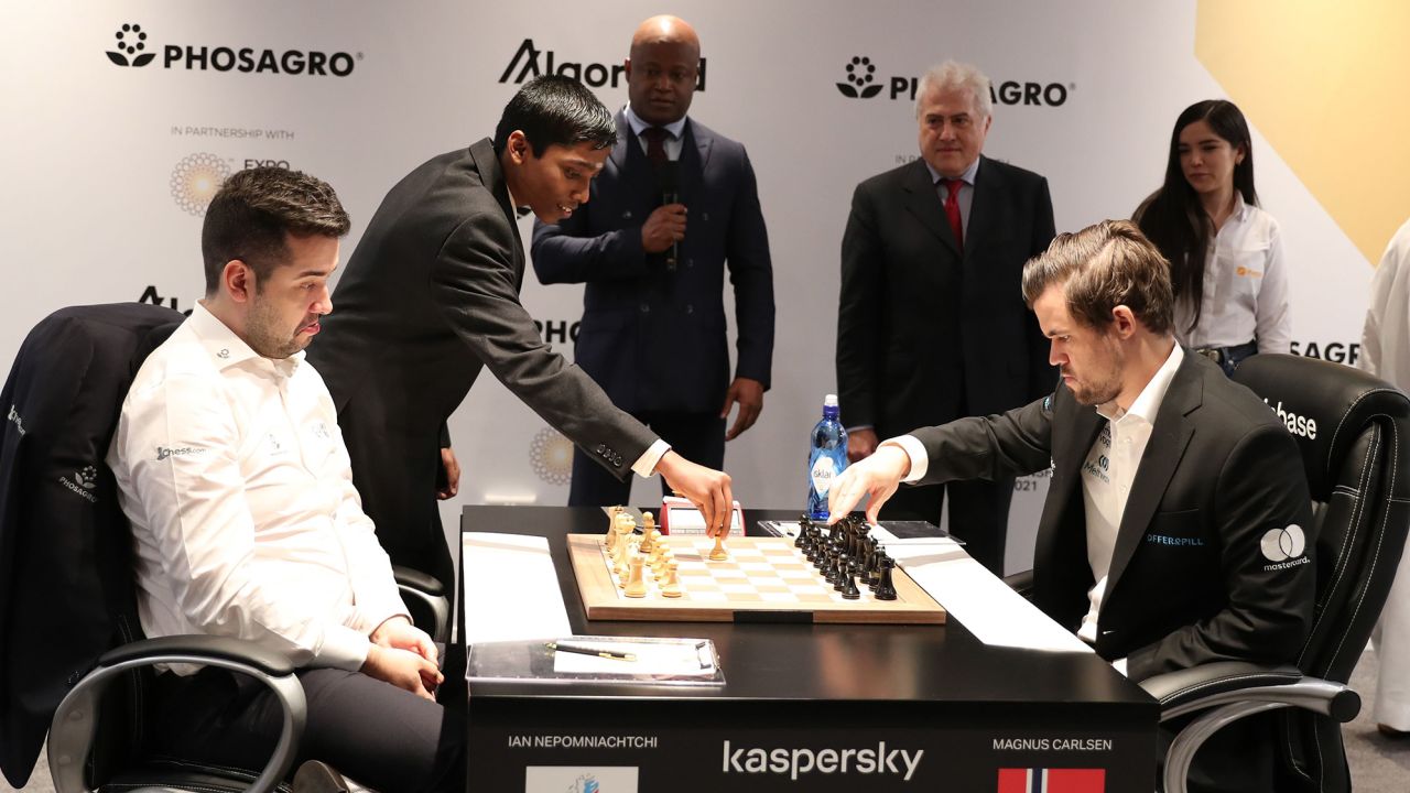 Pragg moving a chess piece at a match between Ian Nepomniachtchi (left) and Magnus Carlsen (right) at the FIDE World Chess Championship at the EXPO 2020 Dubai on December 7, 2021.
