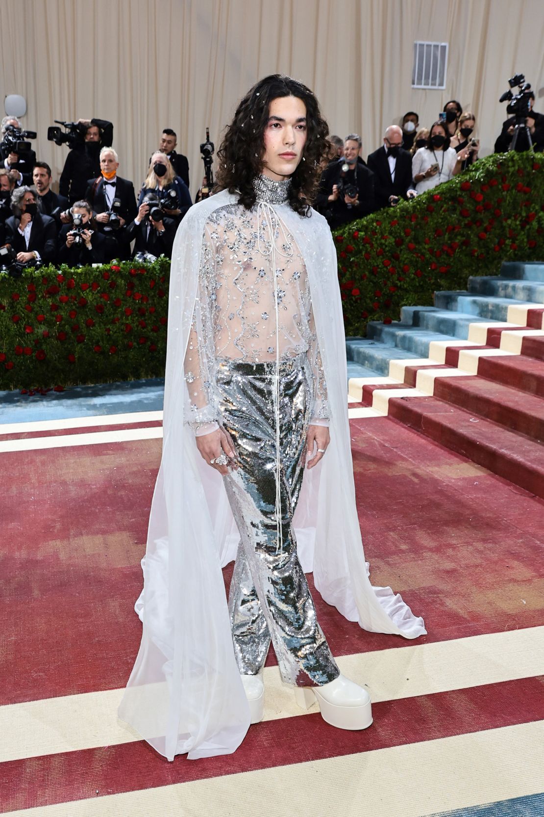 Conan Gray sparkled in a crystal-embellished outfit by Valentino, featuring a sheer mesh shirt, cape and sky high white platforms.