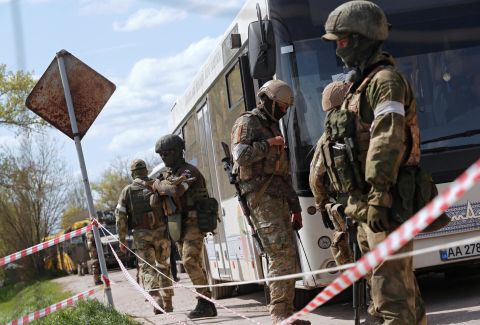 Pro-Russian troops stand guard next to a bus transporting evacuees near a temporary accommodation center in the Ukrainian village of Bezimenne on Sunday, May 1.