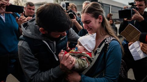 A man welcomes Anna Zaitseva and her 6-month-old son Svyatoslav at a registration and processing area for internally displaced people in Zaporizhzhia.