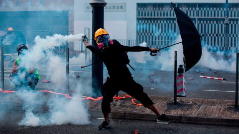 A protester throws back a tear gas canister fired by police in Hong Kong on October 1, 2019.