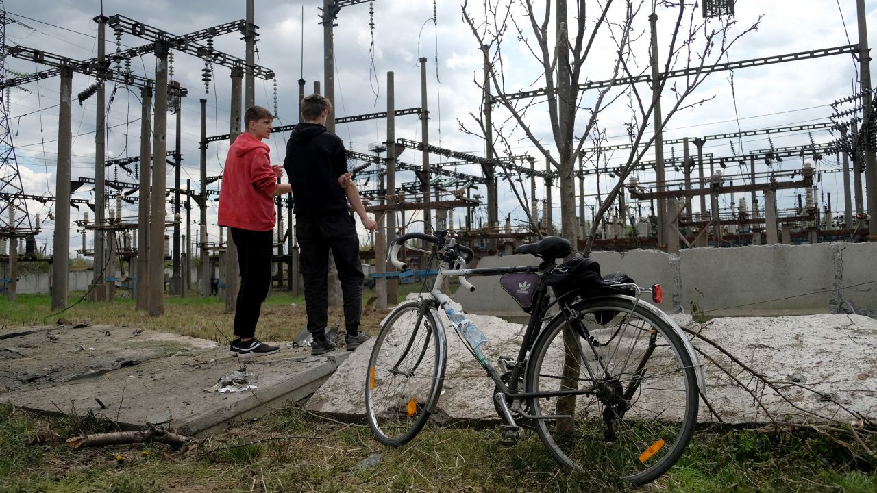Local residents stand next to a railway power station that was damaged by Russian strikes on Tuesday.
