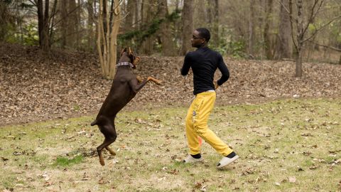 Theodore Wisseh plays with Redtro, the Collab Crib's dog.