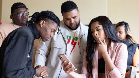 Oneil Rowe, Keith Dorsey and Kaychelle Dabney watch a video on TikTok.